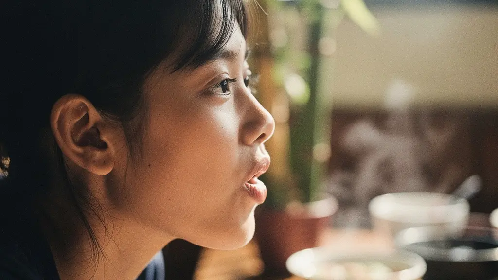 Portrait rapproché d'une personne montrant la position des lèvres pour prononcer correctement le mot Phở, avec une expression concentrée