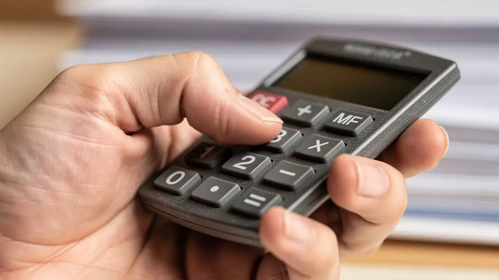 Gros plan sur une main tenant une calculatrice avec des papiers médicaux flous en arrière-plan